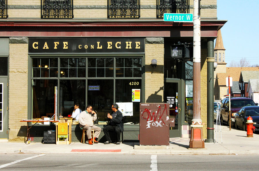 People sitting at a table and chairs outside a cafe