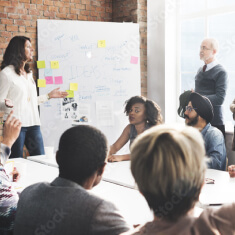 People sitting at table looking at white board during meeting