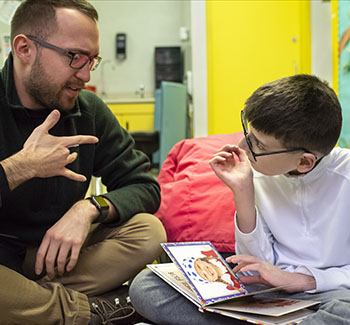 An adult interacting with a reading child