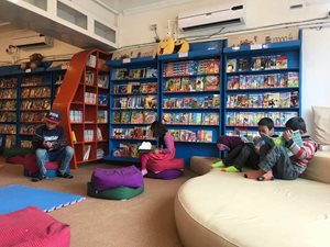 Kids reading children's books in a public library space