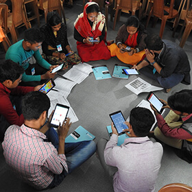 tudents learning English in peer groups using tablets and smart phones.