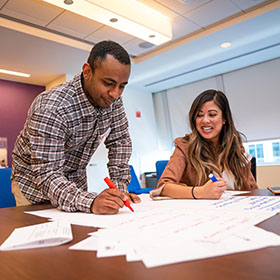 Two people writing at a desk