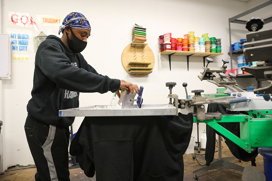 A person wearing a mask operating screen printing equipment