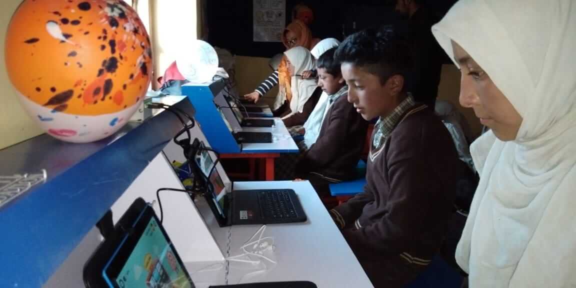 Teacher helps student with math on laptops in a classroom