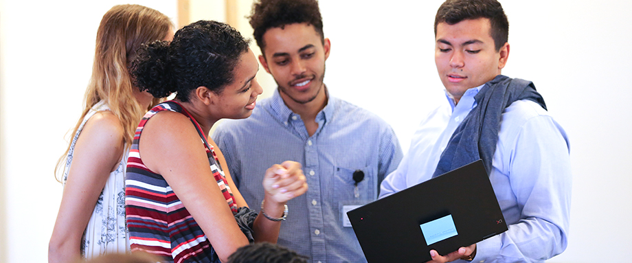 Team members collaborating around a laptop