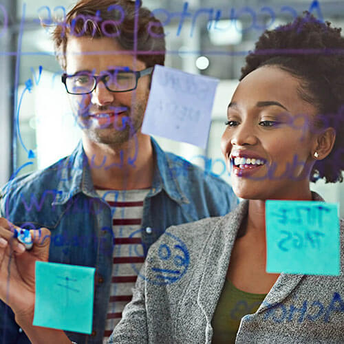 two people stand at a whiteboard planning