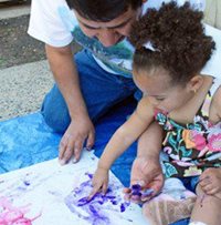 An adult helping a child painting a drawing