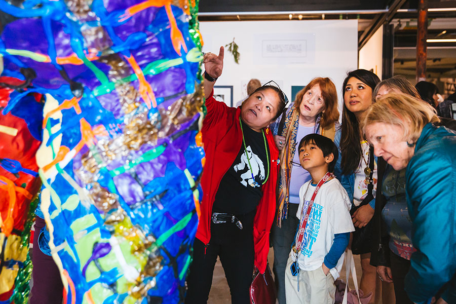 Artist pointing and explaining her sculpture to onlookers