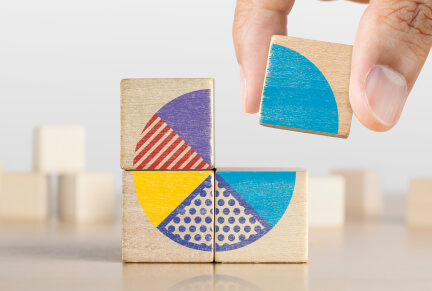 Blocks with picture of pie chart and hand adding last piece