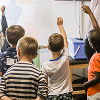 Students raising their hands in a classroom